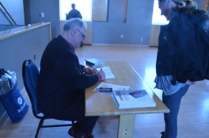 A picture of a man signing a book for a girl.