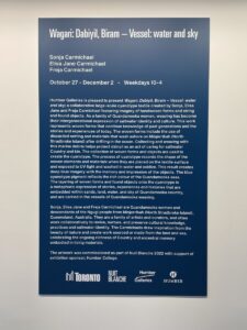 A board about the exhibit which features the artists, dates and time, and the exhibit's description.