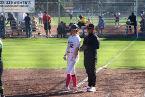 Hannah Koziolek standing on first base right beside assistant coach Brandon Costa.